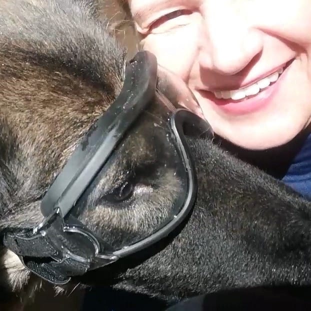 lächelnde Frau mit Hund, der Motorradbrille trägt