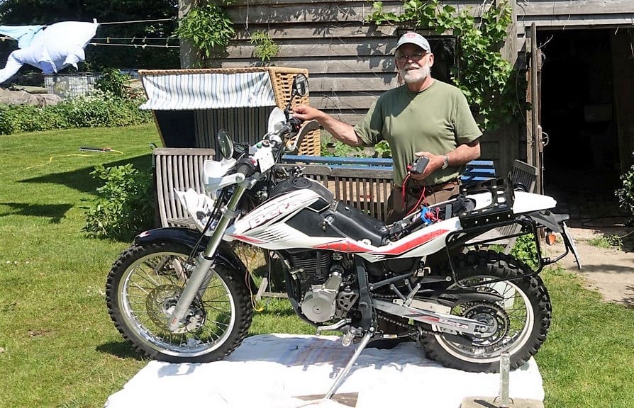Mann mit seinem Motorrad im Garten